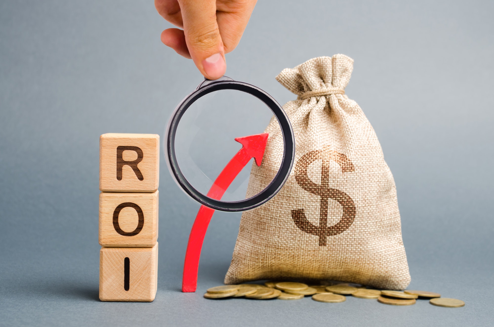 Wooden blocks with the word ROI and the up arrow with the money bag